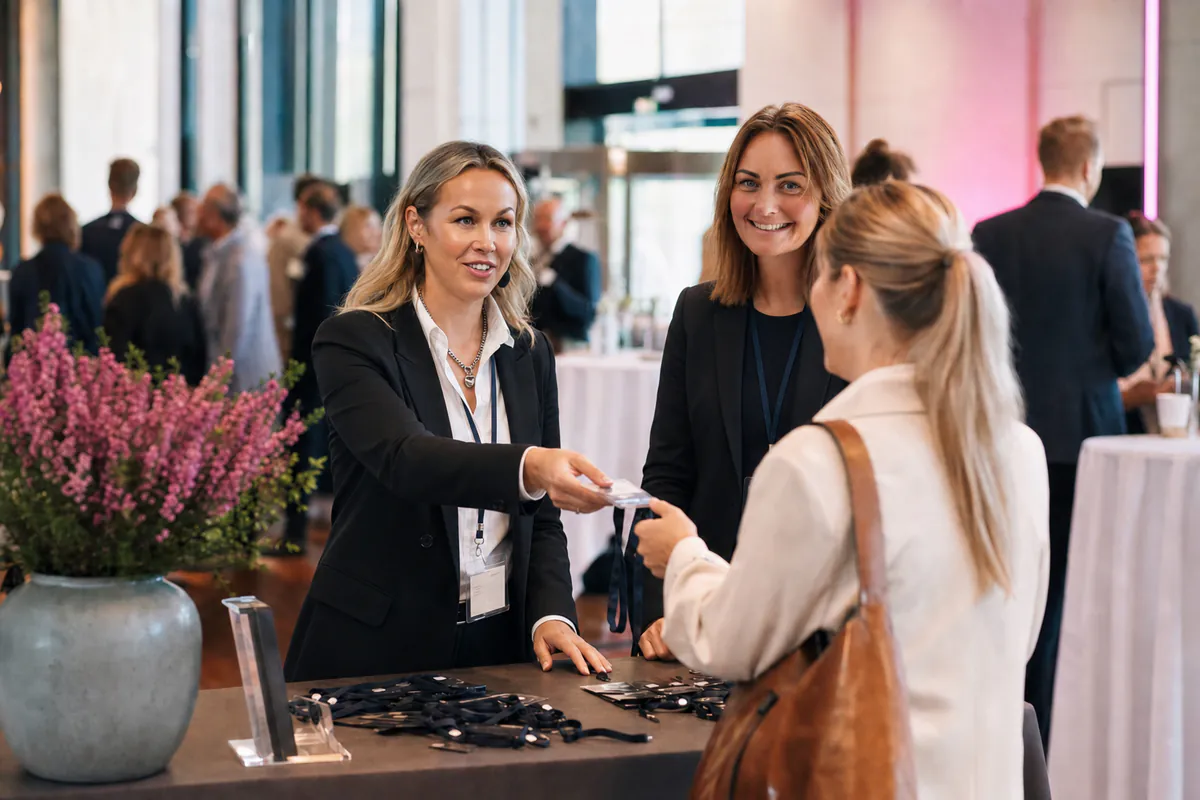 Sophia och Erica välkomnar en deltagare till en konferens